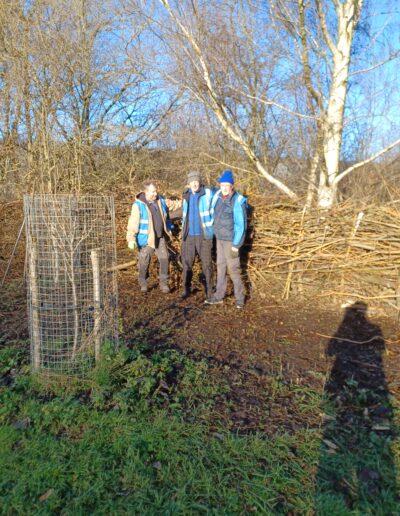 Volunteers in blue high vis jackets standing on a path by a canal